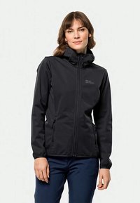 Veste softshell noire avec un col haut, fermeture éclair, deux poches latérales et un logo sur la poitrine. Elle possède une coupe ajustée et une texture lisse.