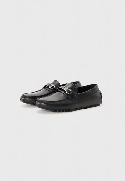 Mustad musta nahast loafers, millel on tekstuuriline viimistlus, hõbedane aksessuaarklips ja kummist tallad väikeste reljeefide jaoks haardumiseks.