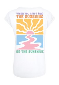 Weißes Baumwoll-T-Shirt mit buntem Grafikdesign. Der Text lautet: "Wenn du die Sonne nicht finden kannst, sei die Sonne" über einem Sonnenaufgang.