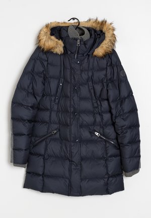 Manteau d'hiver matelassé bleu marine avec capuche bordée de fourrure, fermeture éclair et boutons-pression à l'avant, poches zippées, et poignets gris en maille, suspendu à un cintre noir.