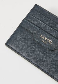 Portafoglio in pelle blu navy con superficie strutturata, dotato di più scomparti per carte e un logo goffrato dorato, rifinito con cuciture a contrasto.