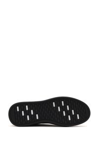 Black rubber shoe sole with a textured design. Features grooves and white accent patterns for traction and grip.