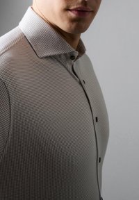 Herrenhemd mit karierter Musterung in hellgrau und dunkelgrau, mit Button-Down-Kragen und schwarzen Knöpfen. Glatte Stoffoberfläche.