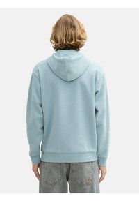 Sudadera con capucha de color azul claro, fabricada en un tejido suave. Cuenta con puños y dobladillo de canalé, un ajuste holgado y un bolsillo tipo canguro en la parte delantera.