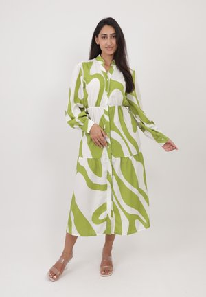 Abito lungo a camicia verde e bianco con una vita aderente, maniche lunghe, chiusura a bottoni e design a strati nella gonna. Tacchi trasparenti.
