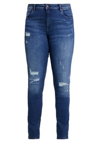 Jeans ajustados en denim azul oscuro con detalles desgastados, que presentan roturas y dobladillos deshilachados, cinturilla de media altura y diseño de cinco bolsillos.