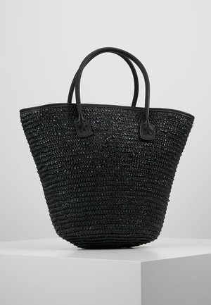 Schwarzer geflochtener Korbtaschen-Shopper mit zwei abgerundeten Griffen, präsentiert auf einem weißen Podest vor einem hellgrauen Hintergrund.