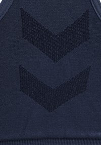 Granatowy stanik sportowy z fakturowanej tkaniny, w kształcie litery V w nieco jaśniejszym odcieniu oraz dopasowanym kroju z wąskimi ramiączkami.