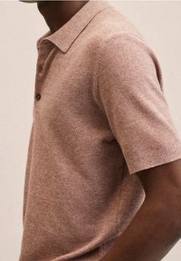 Polo à manches courtes en rose poussiéreux chiné avec un tissage texturé, un col pointu et une fermeture à un bouton au niveau du cou.