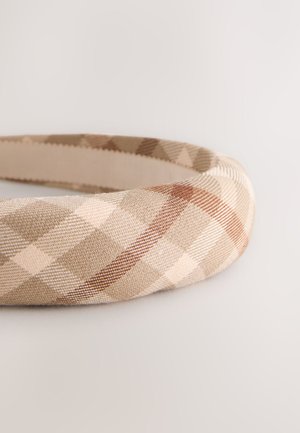 Beige og brun ternet pandebånd lavet af tekstureret stof, med et buet design, en glat inderside og diagonale mønsterdetaljer.