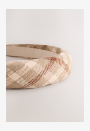 Beige og brun ternet pandebånd lavet af tekstureret stof, med et buet design, en glat inderside og diagonale mønsterdetaljer.