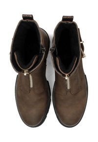 Stivali alla caviglia in pelle marrone con una superficie liscia, dotati di zip dorate, punta rotonda e suole in gomma flat. Rivestiti in tessuto nero.