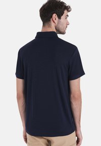 Polo di colore blu navy con una morbida texture, maniche corte e colletto classico. Presenta una vestibilità comoda e un branding discreto sull'orlo.