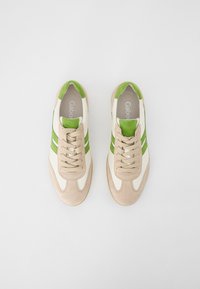 Sneaker beige e bianche con accenti verdi, caratterizzate da un design con lacci, materiali in camoscio e pelle, e una forma della punta arrotondata.
