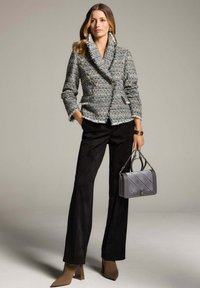 Grijs en blauw gebreide dubbelzijdige jas met grote gouden knopen, gecombineerd met zwarte suède flared broeken en beige puntige hakken. Draagt een grijze gewatteerde tas.