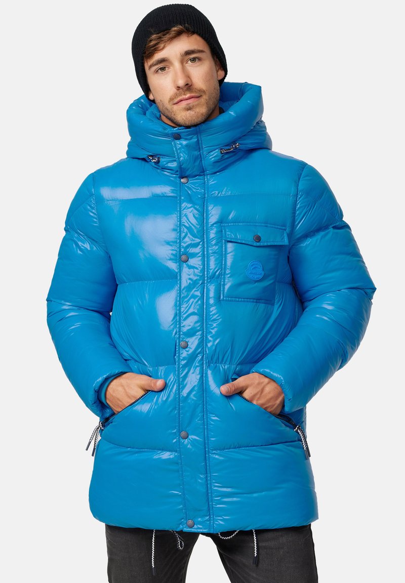 Giacca puffer blu brillante con finitura lucida, grande cappuccio, tasche frontali e zip. Presenta un'etichetta con logo sul petto.