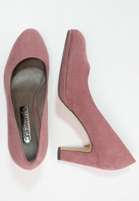 Ein Paar staubig rosa Wildlederschuhe mit hohen Absätzen und runden Zehen, einer von oben und der andere von der Seite auf einem weißen Hintergrund präsentiert.