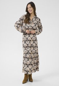 Abito lungo con maniche, botton-down, in un motivo di foglie di palma beige e nero, realizzato in tessuto leggero con una silhouette fluida e orlo arricciato.