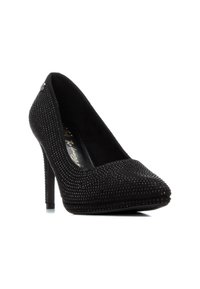 Zapato de tacón alto negro con punta afilada, textura de ante, adornado con pequeños strass en el exterior y un elegante tacón de aguja.