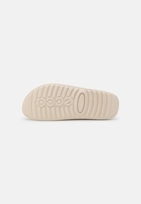 Sole in gomma chiara con scanalature orizzontali e logo in rilievo. Design piatto con punta arrotondata, che offre una superficie liscia.