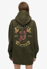 Felpa con cappuccio verde oliva con un grande disegno ricamato sul retro che raffigura un cuore, fiori e un serpente. Include un cappuccio ampio e maniche lunghe.