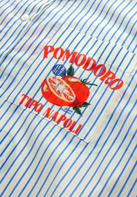 Blue and yellow striped fabric shirt featuring a front pocket with a tomato graphic and red text "POMODORO TIPO NAPOLI."