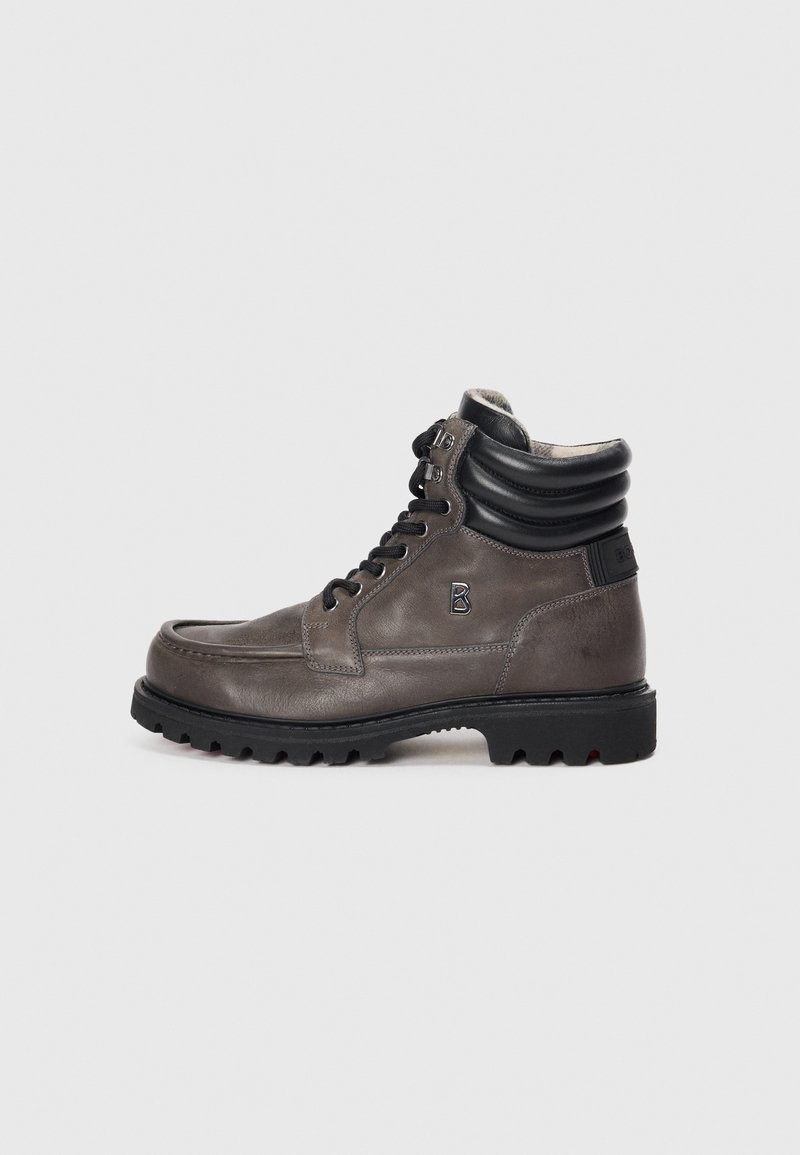 Bottines en cuir gris avec un col rembourré noir, bout rond, semelle extérieure en caoutchouc noir et lacets. Présente un logo en relief sur le côté.