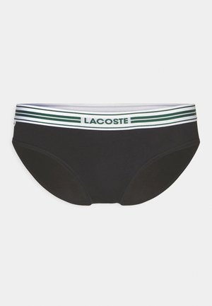 Sorte bikini-truser med en kontrasterende stripete midjebånd i grønn og hvit, med "LACOSTE"-logo. Glatt stoff med en tettsittende design.