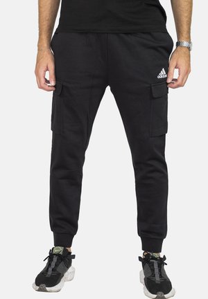 Pantalones cargo negros con bolsillos laterales, cinturilla elástica y puños acanalados. Fabricados con un tejido suave, cuentan con el logo de Adidas en el muslo izquierdo.