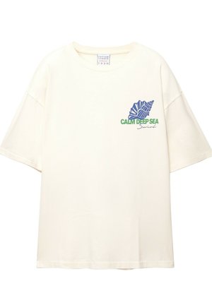 Cream cotton t-shirt with short sleeves. Features a blue shell graphic and “CALM DEEP SEA” text in green. Relaxed fit with a crew neck.