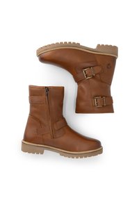 Een paar bruin leren laarzen tot halverwege het kuit met een zijrits, twee verstelbare metalen gespbanden en tan rubberen profielzolen op een witte achtergrond.