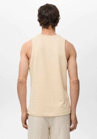 Top in maglia beige a coste con scollatura rotonda, design senza maniche e texture liscia, visto da dietro.