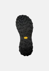 Černá gumová podrážka s agresivním vzorem. Obsahuje žluté logo Vibram blízko středu a má tvar pro lepší trakci.