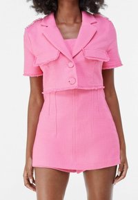 Short pink woven fabric set featuring a cropped blazer with frayed edges and short sleeves, paired with a matching fitted skirt.