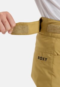 Geel broek met een klittenband-verstelbare tailleband. Voorzien van zwart "ROXY" logo. Soepele textuur met een rechte pijpdesign.