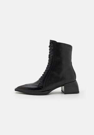 Must mustang kaelasaapad, terava nina, lukuette ja plokknina. Sile tekstuur koos õrna läikega ja minimalistlik disain.