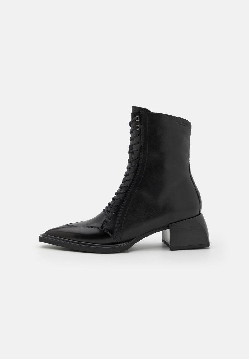 Bottine en cuir noir à bout pointu, avec un laçage à l'avant et un talon épais. Texture lisse avec un léger éclat et un design minimaliste.