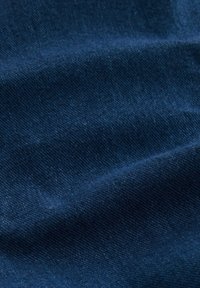 Materialul din denim de culoare albastru întunecat prezintă o textură netedă, cu modele de țesătură vizibile și variații subtile în nuanțe.