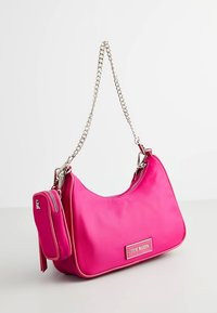 Borsa a spalla in nylon rosa con tracolla a catena, dotata di una patch con logo davanti e di una piccola borsetta zip staccabile attaccata.