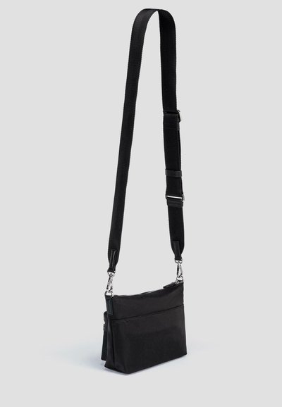 Czarna torba na ramię z trwałego materiału, z długim regulowanym paskiem, zasuwaną główną komorą oraz jedną przednią kieszenią.
