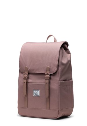 Ružičasti platneni ruksak s poklopcem, dva prednja remena, bočnom džepom i malim logotipom. Teksturirana površina, pravokutni oblik.