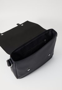 Sac messager noir en cuir lisse avec une fermeture à pression magnétique, un intérieur ouvert et une poche zippée. Accents en métal argenté.