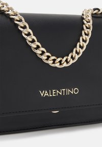 Černá kožená kabelka se zlatým řetízkovým popruhem, s logem "VALENTINO" ve zlaté barvě a jednoduchými švy. Hladká textura, obdélníkový tvar.