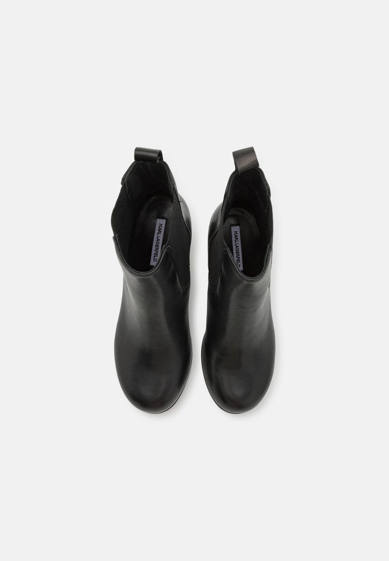 Bottines noires en cuir lisse, avec un design ajusté, un bout rond et des languettes à l'arrière pour un enfilage facile.
