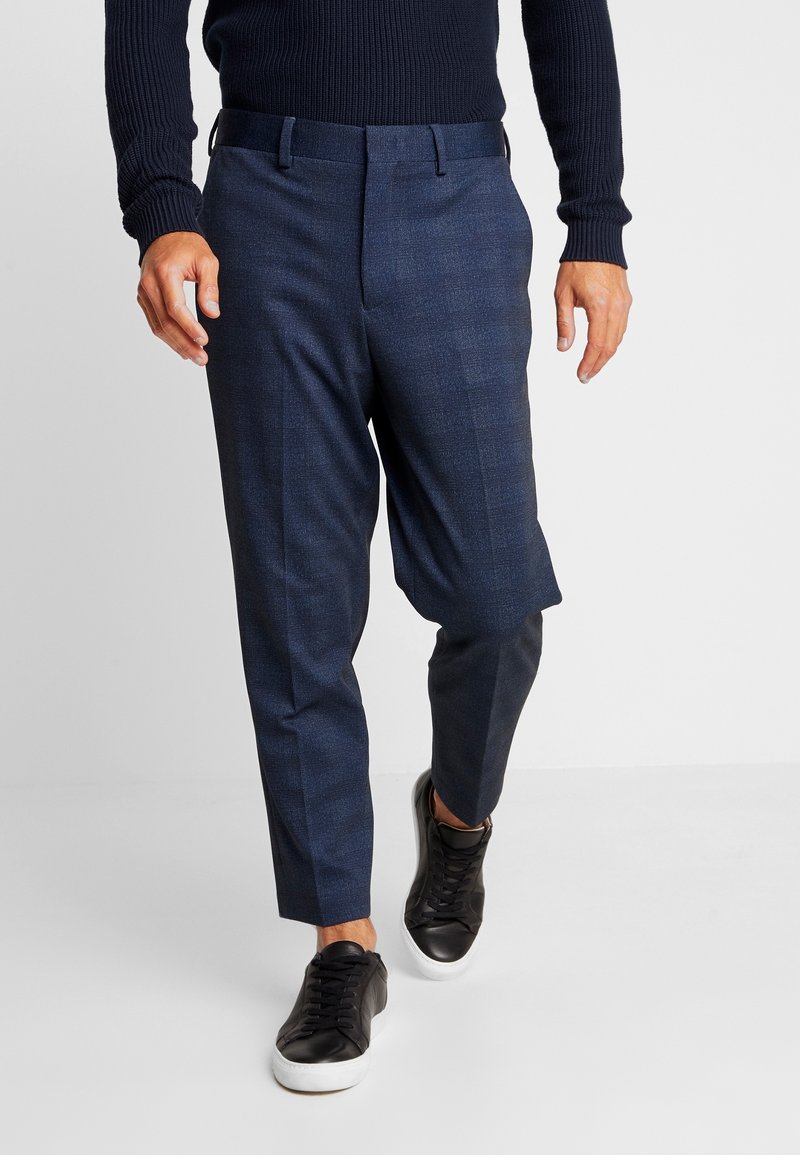 Navy check tailored trousers, lightweight fabric, straight leg, button and zip closure, paired with black sneakers.