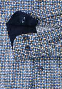 Overhemd met knopen, gekenmerkt door een geometrisch patroon in blauw, geel en wit, met een marineblauwe kraag en bijpassende knopen. De textuur lijkt glad.