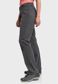 Grau Outdoor-Hosen aus strapazierfähigem Stoff mit slim fit, seitlichen Taschen und verstellbarem Bund, kombiniert mit grauen Wanderschuhen.