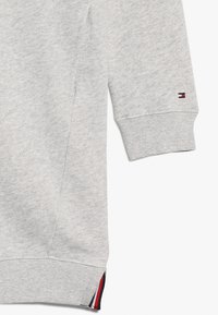 Harmaa collegepaita, jossa on teksturoitu pinta, rib clot och sivusauma. Hihassa on pieni merkkilogo punaisena, valkoisena ja sinisenä.