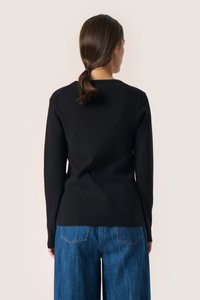 Pulover negru cu mâneci lungi și guler rotund, fabricat dintr-un material tricotat neted. Asortat cu pantaloni din denim albastru cu picior larg.