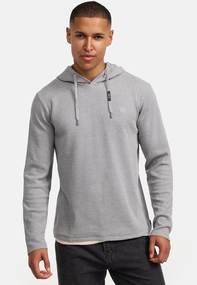 Gray ribbed hoodie with a kangaroo pocket and adjustable drawstrings. Long sleeves and a relaxed fit, layered over a light-colored shirt.